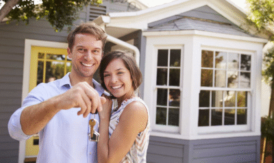 A couple with keys standing in front of their new home that had everything on their wishlist.